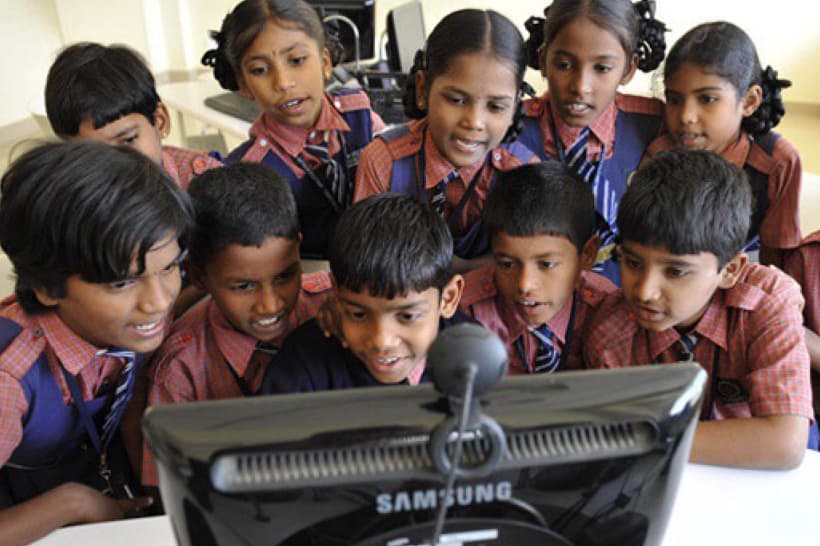 School children gathered around a desktop computer